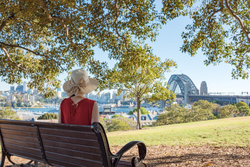 Woman sitting on a bench and looking at Sydney Harbour