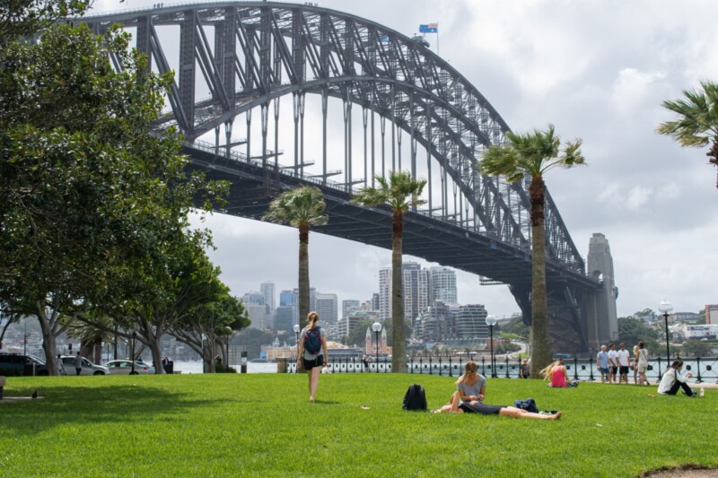 Panoramic view of the people relaxing at a park next to the Sydney Harbour Bridge in Australia