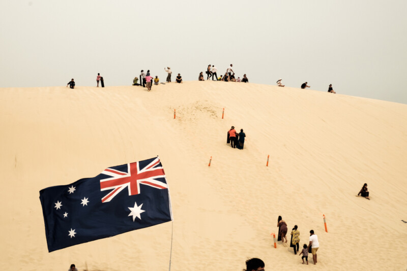 Groups of tourists were playing and sliding sand boards on sand dunes
