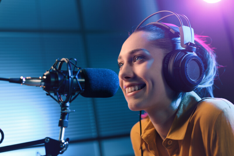 Young smiling woman wearing headphones and talking into a microphone