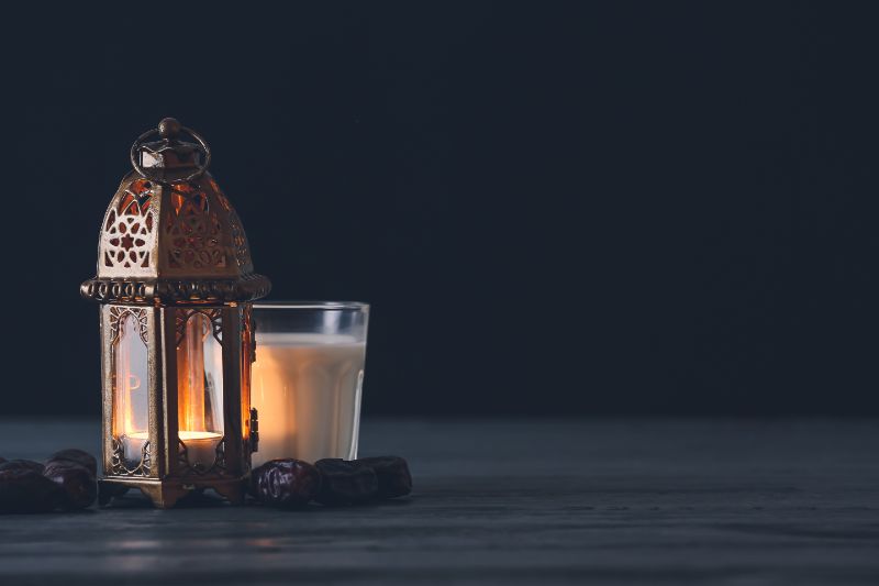 Muslim lamp, glass of milk and dates on dark background