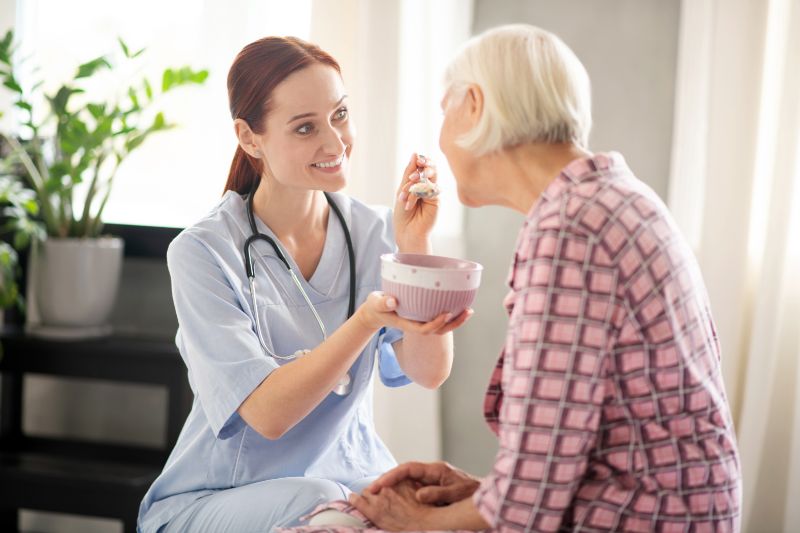 Nurse feeding elderly patient