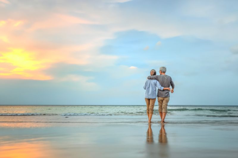 Senior couple walking on the beach holding hands at beach sunrise
