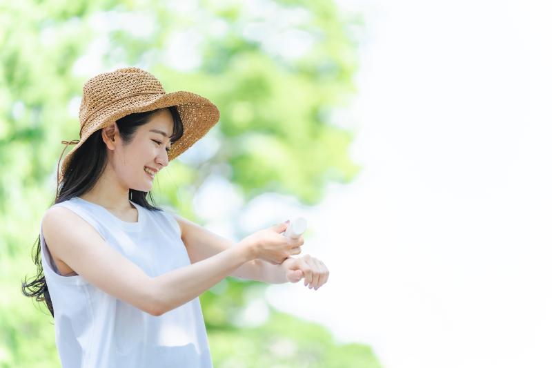 Woman with hat applying sunscreen