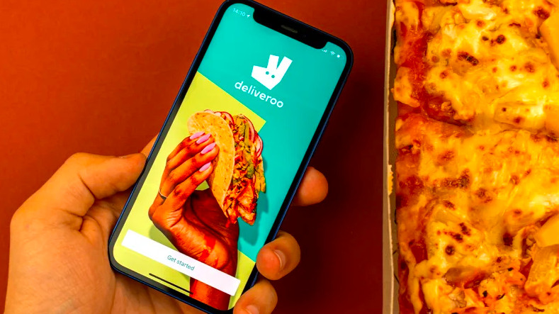 Hand with smartphone showing Deliveroo app